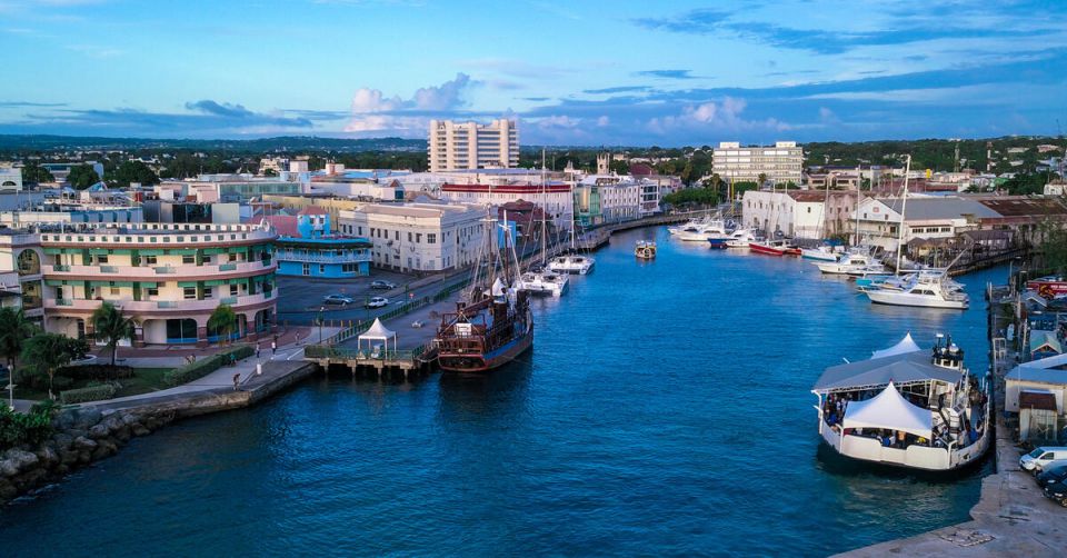 An aerial view of buildings near a body of water. There are boats in the water and clouds in the sky.